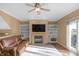 Cozy living room featuring a fireplace, built-in bookshelves, ceiling fan, and access to a deck at 9877 Wading Crane Ave, Fishers, IN 46055