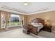Spacious main bedroom features a tray ceiling, large window views, and traditional-style furniture at 9877 Wading Crane Ave, Fishers, IN 46055