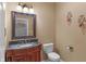 Cozy powder room featuring a wooden vanity with a granite countertop, and decorative sconces at 9877 Wading Crane Ave, Fishers, IN 46055