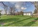 Expansive backyard with lush green grass, mature trees, and a charming home in the distance at 102 E Thompson St, Lebanon, IN 46052