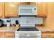 The stove is paired with oak cabinets, matching countertops, and white microwave at 102 E Thompson St, Lebanon, IN 46052