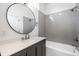 Modern bathroom featuring gray subway tiles, a round mirror, and a sleek vanity with white countertop at 1026 St Peter St, Indianapolis, IN 46203