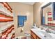 Well-lit bathroom with a single sink vanity and a shower featuring a striped curtain at 10407 Stillwell Ct, Avon, IN 46123