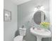 Stylish powder room featuring pedestal sink, round mirror, and elegant fixtures at 108 Wesley Cir, Noblesville, IN 46062