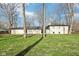 A grassy backyard features bare trees, the back of a home, and a firepit area with a wooden fence at 11921 Westwood Dr, Carmel, IN 46033