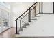 Bright foyer with white walls and staircase featuring dark railings and wood-look flooring at 11921 Westwood Dr, Carmel, IN 46033