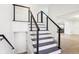 Modern staircase with black railing and gray steps in a bright, white interior at 11921 Westwood Dr, Carmel, IN 46033