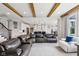Open concept living room with a cozy leather sectional, wood beams, and open flow to the kitchen at 14747 Harvest Glen S Blvd, Fishers, IN 46037