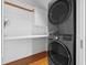 Bright laundry room with stacked washer and dryer, shelving, and hardwood floors at 1537 Carrollton Ave, Indianapolis, IN 46202