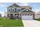 Two-story home featuring a brick facade and green siding, plus a well-manicured lawn and two car garage at 1695 Jackson St, Fortville, IN 46040