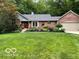 Beautifully landscaped brick home with mature trees, green lawn, and attached garage at 2143 Sunderland Dr, Martinsville, IN 46151