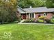 Charming brick home with a well-manicured front yard, mature landscaping, and a red front door at 2143 Sunderland Dr, Martinsville, IN 46151
