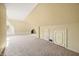A large unfinished attic with patterned wallpaper, carpet, dormer window, and built-in storage solutions at 2309 Pearl St, Columbus, IN 47201