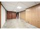 Unfinished basement showing paneled walls, a brick accent wall, exposed ceiling, and concrete flooring at 2309 Pearl St, Columbus, IN 47201