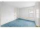 A bright, cozy bedroom with blue carpeting, white walls, a door, and a window at 2309 Pearl St, Columbus, IN 47201
