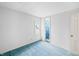 A minimalist bedroom with blue carpet, white walls, and a doorway leading to the blue floral bathroom at 2309 Pearl St, Columbus, IN 47201