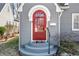 Close up of charming gray home's red arched front door, front steps, and landscaped lawn at 2309 Pearl St, Columbus, IN 47201