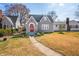 View of charming gray home with a red arched entry door, gray roof, and a traditional lawn with spring color at 2309 Pearl St, Columbus, IN 47201