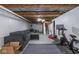 This basement has exposed unfinished ceiling, painted walls, large gray couch, peloton, and a gray rug at 3636 N Chester Ave, Indianapolis, IN 46218