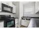 Cozy kitchen features white cabinets, dark countertops, and modern black appliances at 3704 Graceland Ave, Indianapolis, IN 46208