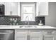 Modern kitchen with white cabinets, gray backsplash, and stainless steel appliances at 3712 N Olney St, Indianapolis, IN 46218