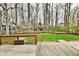 View of the backyard from the wooden deck, with green grass, mature trees, and a partial fence at 381 Stoneybrook Grove Dr, Greenwood, IN 46142