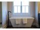 Close-up of a modern white soaking tub with matte black faucet, and a bright window above at 3899 Chapel Hill Ct, Bargersville, IN 46106