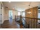 Hallway with brick accent wall, iron and wood railing, hanging light fixtures and view to the living room at 3899 Chapel Hill Ct, Bargersville, IN 46106