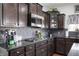 Close up of kitchen features, including dark cabinets, granite countertops, stainless steel microwave, and gas cooktop at 4846 Shakamak Ct, Indianapolis, IN 46239