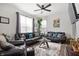 Spacious living room featuring dark leather sofas, a ceiling fan, and natural light from large windows at 4846 Shakamak Ct, Indianapolis, IN 46239