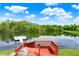 A red deck overlooks a calm lake, enhanced by an adjacent boat dock and a beautiful, sunny sky backdrop at 5571 Poff Rd, Martinsville, IN 46151