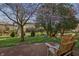 Relaxing backyard with Adirondack chairs, mature trees, and a glimpse of the home's exterior at 6140 Buttonwood Dr, Noblesville, IN 46062