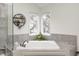 Bright bathroom featuring a soaking tub with gray stone surround and twin windows at 7002 Oakbay Cir, Noblesville, IN 46062