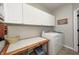 Well-organized laundry room with white cabinets, washer, dryer, and folding table at 7002 Oakbay Cir, Noblesville, IN 46062