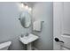 Charming powder room featuring a pedestal sink, decorative mirror, and elegant lighting at 7002 Oakbay Cir, Noblesville, IN 46062
