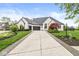Striking white brick home featuring a three-car garage, meticulously landscaped front yard, and curved driveway at 7259 Josiah Ct, Indianapolis, IN 46259