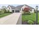 Charming white brick home featuring a three-car garage, well-manicured lawn, and decorative landscaping at 7259 Josiah Ct, Indianapolis, IN 46259