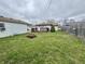 Green backyard with fire pit featuring a small deck and mature tree at 7367 Parkside Dr, Indianapolis, IN 46226