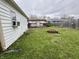 Green backyard with fire pit featuring a small deck and mature tree at 7367 Parkside Dr, Indianapolis, IN 46226