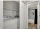 Efficient laundry area with white appliances and added shelving near a tiled bathroom at 7783 Park N Ct, Indianapolis, IN 46260