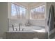 Bright bathroom featuring a soaking tub with marble surround and views from two large windows at 7980 S State Road 135, Columbus, IN 47201