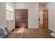 A bright bedroom features wood floors, a sliding closet door, and a view into the laundry area at 7980 S State Road 135, Columbus, IN 47201