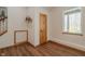 Hallway with wood-look floors, wooden door, window, and staircase access at 7980 S State Road 135, Columbus, IN 47201