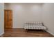 An open room has wood floors, a wooden door, and a plaid-patterned futon couch at 7980 S State Road 135, Columbus, IN 47201