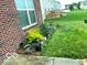Brick home's backyard showcases a garden area, lush green grass, and a concrete patio at 8744 N Aspen Way, McCordsville, IN 46055