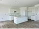 Kitchen features white cabinets, an island with a sink, and light countertops with wood-look floors. Ready for appliances! at 905 Saddlebrook Farms Blvd, Whiteland, IN 46184