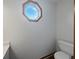 Bright bathroom featuring a modern octagonal window, white toilet, and vanity with stylish countertop at 9237 Stones Ferry Pl, Indianapolis, IN 46278