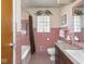 Pink tiled bathroom featuring a tub, toilet, and vanity with pink countertop at 1035 N Audubon Rd, Indianapolis, IN 46219