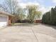 Wide driveway with mature trees and side load garage at 1035 N Audubon Rd, Indianapolis, IN 46219