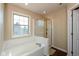 Bright bathroom showcasing a bathtub with a tiled surround, a framed window, and an enclosed glass and gold shower at 1083 Sugar Maple Dr, Greenwood, IN 46143
